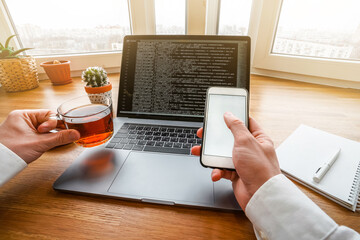 Canvas Print - the man works with modern technologies, a laptop and a mobile phone. top view of a programmer or bus