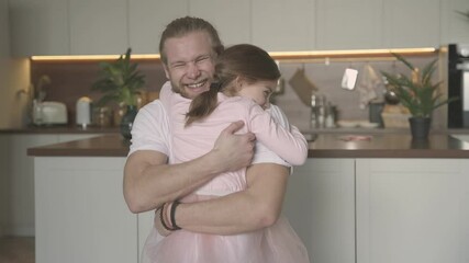 father's day. little daughter dressed as a princess hugs her daddy at home.