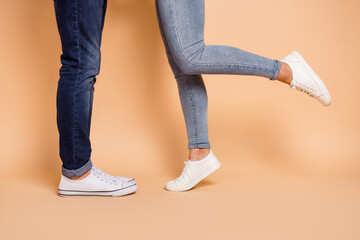 Poster - Cropped photo of girlfriend boyfriend legs in jeans sneakers date romantic feelings isolated over beige color background