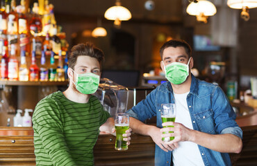 Canvas Print - friendship, health and st patrick's day concept - happy male friends wearing face protective medical mask for protection from virus disease drinking green beer at bar or pub