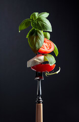 Mozzarella with tomato and basil on a fork.