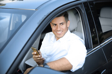 Wall Mural - Handsome man using smartphone in modern car