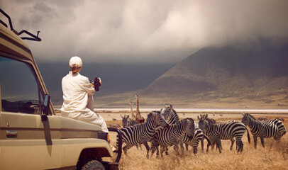 woman traveler on safari-tour in africa, traveling by car in tanzania, watching wild animals and bir