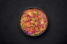 Pancit Bihon In Black Bowl On Dark Slate Table Top. Filipino Cuisine Noodles Dish With Pork Belly, Chicken, Vegetables. Asian Food. Top View