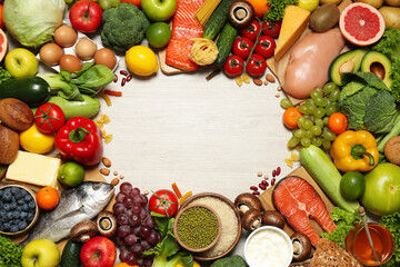 Frame of different food products on wooden table, flat lay with space for text. Healthy balanced diet