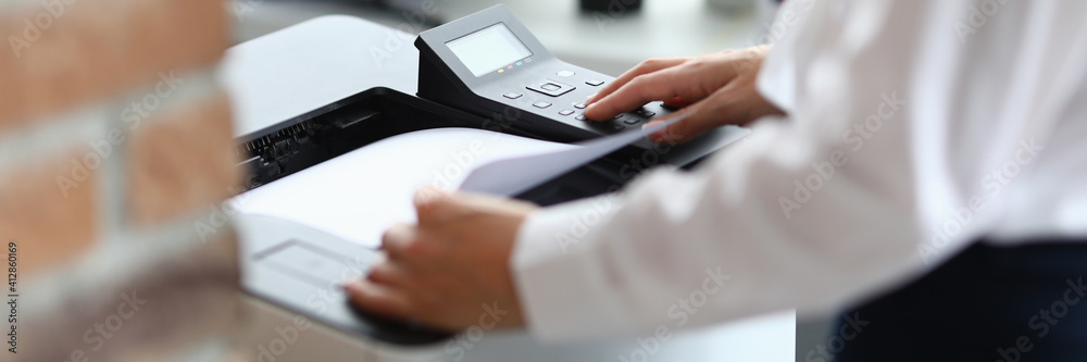 Woman in office prints documents on printer. Scanning documents at workplace concept - obrazy, fototapety, plakaty 