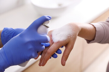 Poster - Applying burn spray onto injured skin, closeup