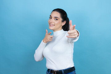 Wall Mural - Young caucasian woman wearing white sweater over blue background