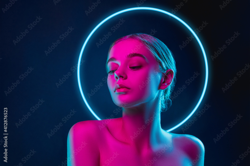Future. Portrait of female fashion model in neon light with neoned blue glowing circle on dark studio background. Beautiful woman with trendy make-up and well-kept skin. Vivid style, beauty concept. - obrazy, fototapety, plakaty 