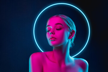 future. portrait of female fashion model in neon light with neoned blue glowing circle on dark studi