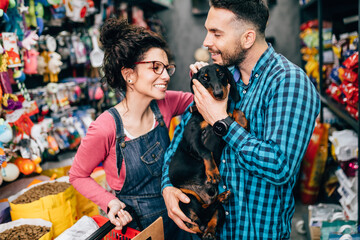 Wall Mural - Happy couple buying toys and food for their Dachshund in pet shop.