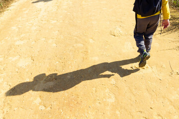 Child on his back walking on a dirt road.