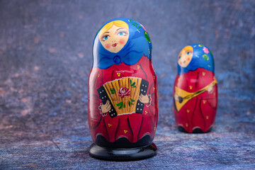 Matryoshka dolls in blue handkerchiefs, with an accordion, and a balalaika on a dark colorful background