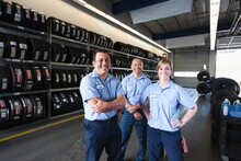Portrait Of Smiling Mechanics In Auto Repair Shop, Two Men And A Woman