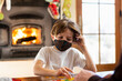 © Mint Images - young boy wearing mask playing board game at home