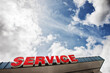 © Mint Images - Auto service sign against partly cloudy blue sky viewed from below