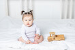 © Any Grant - baby girl playing wooden toy typewriter on the bed at home, the concept of play and development of children