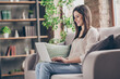 © deagreez - Profile side photo of young brunette woman sit sofa good mood use laptop work home inside house indoors