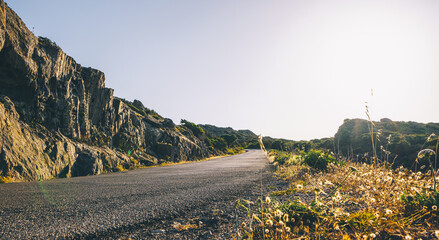 Wall Mural - Empty long mountain road to the horizon on a sunny summer day at bright sunset