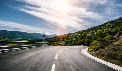 Empty long mountain road to the horizon on a sunny summer day at bright sunset