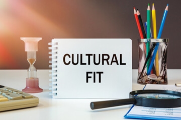 CULTURAL FIT is written on a notepad on an office desk