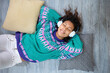 © Alfredo López - Close up of brunette girl enjoying her leisure time listening to music lying on the floor of her house. Space for text.