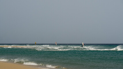 Canvas Print - Beautiful shot of a sea with the windsurfers in a wavy sea under the clear sky