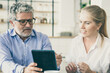 © Mangostar - Focused friendly mature male mentor explaining work details to intern. Business man showing tablet screen to young female colleague. Medium shot. Communication or teamwork concept
