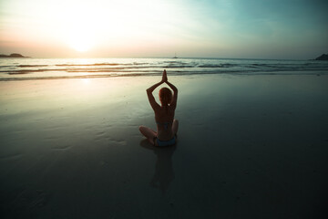 Wall Mural - Yoga woman meditation on sunset sea coast.