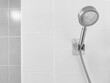 Closuep of stainless steel head shower with blurry white and gray tile wall in the bathroom.