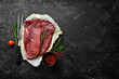 Two raw veal steaks with rosemary and spices. On black stone background. Top view.