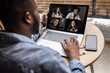 © shunevich - Back view. African-American worker discusses brainstorming video call with various colleagues, screen view of racial colleagues conducts team conference on webcam, participates in online briefing.