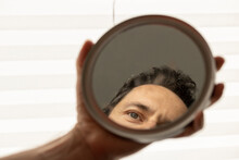 Cropped Hand Of Man Holding Mirror With Reflection