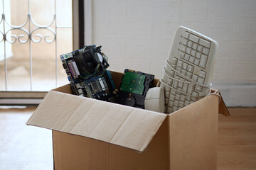 Old hard disk dive and motherboards and used keyboard with mouse old computer hardware accessories in paper boxes, Obsolete equipment is electronic waste Reuse and Recycle concept.