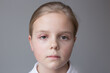 Selective focus, concept. Girl 10 years old portrait. One eye has barley. Grey background.