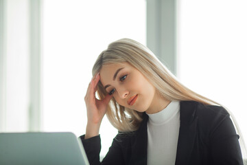 beautiful young woman in a suit at the office at the table with a laptop 