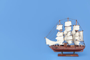 Sticker - Miniature model of old ship with white sails on blue background, space for text