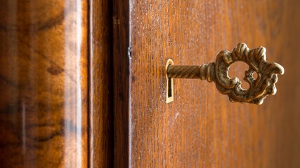 Old key in a keyhole of an old wooden wardrobe . Security concept. Wood detail 