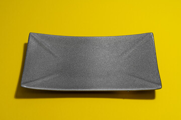 empty dark plate on yellow background