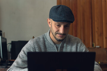 Poster - Closeup shot of a male wearing a hat working on his computer