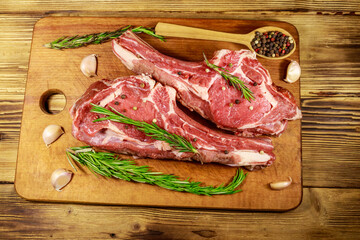 Sticker - Raw fresh beef rib eye steak on bone with spices, garlic and rosemary on wooden table. Top view