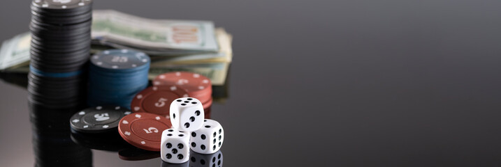 Chips, cards and dice for a casino game on a black background with reflection. The concept of gambling and entertainment. Casino and poker