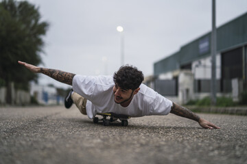 Sticker - Shallow focus shot of a handsome smiling European guy lying on a skateboard