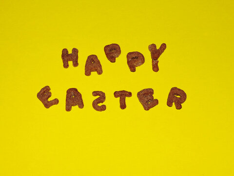 funny happy easter lettering made of quick breakfast edible sweet letters on yellow background