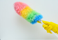 A Woman's Hand In A Yellow Rubber Glove. There's A Feather Duster In This Hand. White Background. Concept-hygiene, Maintaining Cleanliness