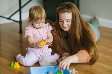 Wall Mural - A young mother and her one and a half year old daughter are sculpted from kinetic sand. Development of motor skills