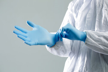 Wall Mural - Doctor in a protective medical suit puts on blue rubber gloves