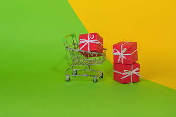 Minimal concept idea made of shopping cart full of gift box on green and illuminating yellow and green color background.