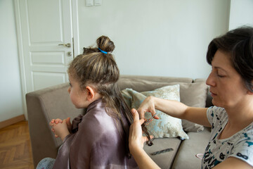 young woman is cutting her daughter's hair at home during the pandemic. stay at home.