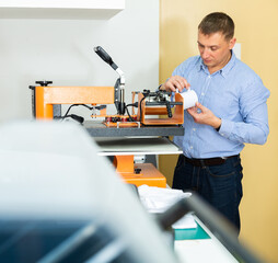 Wall Mural - Man uses machine to print on ceramic mug. High quality photo